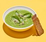A bowl of green soup made with courgette, leek and goat's cheese served with bread