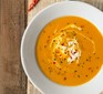 Butternut squash and chilli soup in a bowl, with a swirl of cream