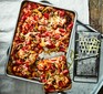 Pizza with chicken and cheese in baking pan with slice cut