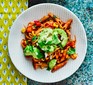 Tomato penne with avocado on a white plate