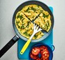 Omelette cut into quarters in pan with spatula and tomatoes