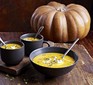 Creamy pumpkin & lentil soup in a black bowl and two mugs