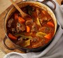 Beef & vegetable stew in a cast iron pot with wooden spoon