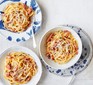 Spaghetti with pancetta and cheese in bowls with cutlery